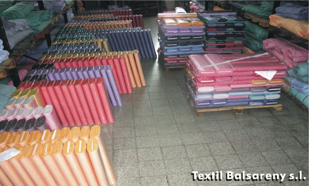 Piezas de tela de muchos colores apiladas en el suelo del almacén